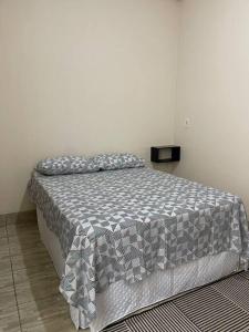 a bed with a gray and white comforter in a bedroom at Apartamento próximo ao centro in Primavera do Leste