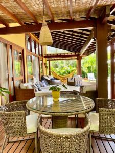 an outdoor patio with a glass table and chairs at Costa do Sauipe Casa dentro do complexo hoteleiro in Costa do Sauipe