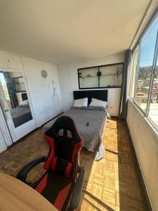 a bedroom with a bed and a chair and a window at Departamento centro de Viña in Viña del Mar