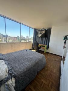 a bedroom with a bed and a desk and windows at Departamento centro de Viña in Viña del Mar