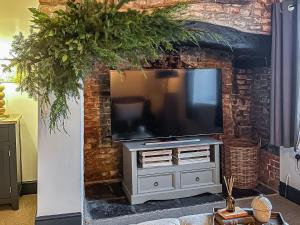 ein Wohnzimmer mit einem TV an einer Backsteinwand in der Unterkunft The Old Smithy in West Ashton