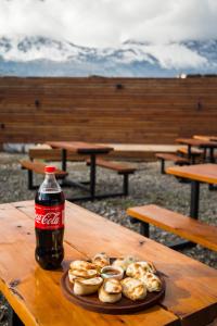 une bouteille de soda et une assiette de beignets sur une table dans l'établissement Big Hostel, à El Bolsón