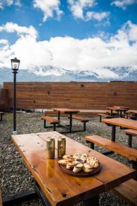 einem hölzernen Picknicktisch mit einem Teller Essen drauf in der Unterkunft Big Hostel in El Bolsón