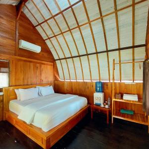 Sunari Beach Resort 2 في Selayar: غرفة نوم بسرير في غرفة خشبية