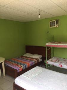 Habitación con 2 camas y pared verde. en Hostal Camping Beach, en Salinas