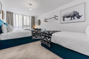 sypialnia z dwoma łóżkami i zdjęciem nosorożca w obiekcie Earthy Elegance: Nature Inspired Flat in Prime Location w Londynie