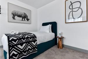 a bedroom with a bed and a picture of a rhino at Earthy Elegance: Nature Inspired Flat in Prime Location in London