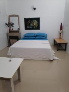 a bedroom with a bed and a table and a mirror at The Rose Garden House in Hithadhoo