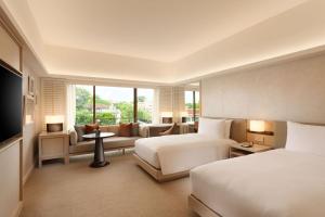 a hotel room with two beds and a couch at Conrad Singapore Orchard in Singapore