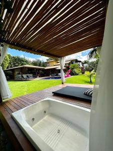 une baignoire assise sur une terrasse avec un toit en bois dans l'établissement Costa do Sauipe Casa dentro do complexo hoteleiro, à Costa do Sauipe