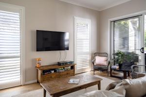 un soggiorno con una TV a schermo piatto su una parete di Aria Shores - Your Lakeside Haven a Burrill Lake
