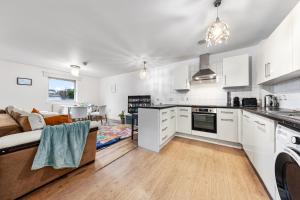 a kitchen and living room with white cabinets and a couch at Modern Spacious 1 Bedroom Flat in Camden in London