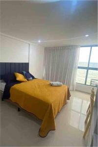 - une chambre avec un lit doté d'une couverture jaune et d'une fenêtre dans l'établissement Pé na areia com vista mar 203, à João Pessoa