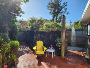 a patio with a yellow chair and a table at 'Haumoana' in Olde Beach. in Waikanae