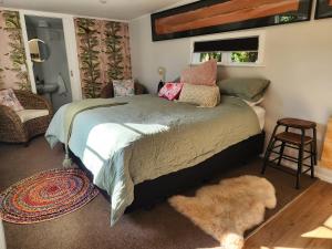 a bedroom with a bed and a stool and a window at 'Haumoana' in Olde Beach. in Waikanae