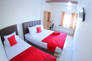 grand koetaradja permai hotel في Luengbata: غرفة نوم بسريرين بملاءات حمراء وبيضاء