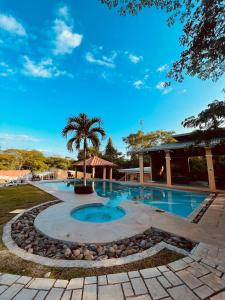 una piscina con una palmera y un edificio en Villas jr estudio 1 by Oasis Guacalillo, en Tarcoles