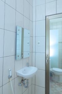 La salle de bains blanche est pourvue d'un lavabo et de toilettes. dans l'établissement grand koetaradja permai hotel, à Luengbata