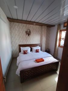 a bedroom with a bed with white sheets and red pillows at Snowline Homestay in Kīar