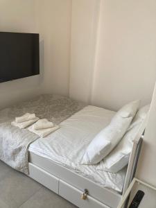 ラスパルマス・デ・グランカナリアにあるAstoria Studio Home for Beach Holidayのベッド(白いシーツ、枕付)、薄型テレビが備わります。