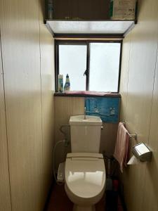 ein kleines Bad mit einem WC und einem Fenster in der Unterkunft Snow Fever - Clan in Hakuba