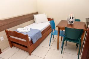 a small room with a bed and a table and chairs at Pousada Roberto Monteiro - Frente Mar in Florianópolis