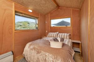 a bedroom in a tiny house with a bed at Karo Hut A - Ninety Mile Beachfront Cabin in Awanui