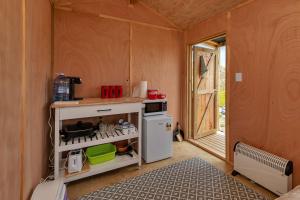 una pequeña cocina con fogones y nevera. en Karo Hut A - Ninety Mile Beachfront Cabin en Awanui