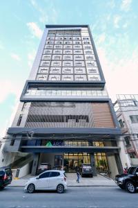 un edificio alto con coches estacionados frente a él en Ardenhills Suites en Manila