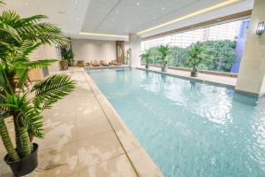 a large swimming pool in a building with a palm tree at Ardenhills Suites in Manila