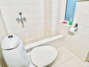 La salle de bains blanche est pourvue de toilettes et d'une fenêtre. dans l'établissement Shanthi Home Stay, à Puttaparthi