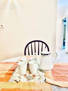 a table with three tea cups and a tea pot at Shanthi Home Stay in Puttaparthi