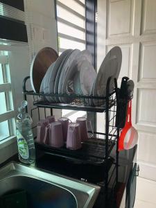 um suporte de pratos cheio de pratos e pratos num lavatório em ZDH Homestay em Kota Bharu