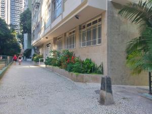 a woman walking down a sidewalk next to a building at URCA 303 Rio BR in Rio de Janeiro
