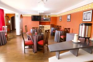 a dining room with tables and chairs and orange walls at Hoteles Riviera Cayma in Arequipa