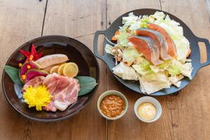 zwei Teller Essen auf einem Holztisch in der Unterkunft ウッドデザインパーク瀬戸 in Seto