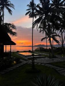 puesta de sol desde un complejo con palmeras en WOODEN HOUSE CANDIDASA en Manggis