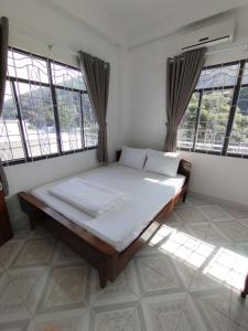 a large bed in a room with windows at Nhà Nghỉ SAO MAI in Ha Tien