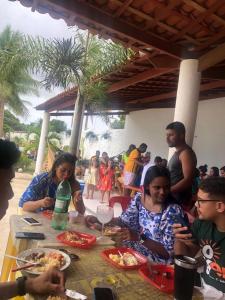Grupa ludzi siedzących przy stole jedzących pizzę w obiekcie Chácara coqueiral w mieście Estância