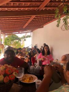 um grupo de pessoas sentadas à mesa com comida em Chácara coqueiral em Estância