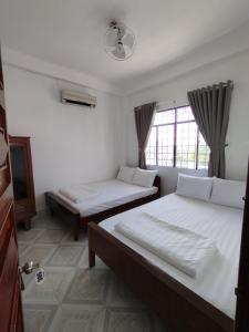 1 dormitorio con 2 camas y ventana en Nhà Nghỉ SAO MAI, en Hà Tiên