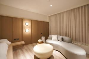 a bedroom with a white couch and a stool at Hope Hotel Tainan - Minsheng Branch in Tainan