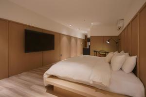 a bedroom with a white bed and a flat screen tv at Hope Hotel Tainan in Tainan