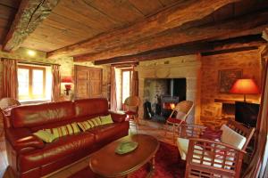 a living room with a leather couch and a table at Le masbareau, gite le vieux domaine in Royères-Saint-Léonard