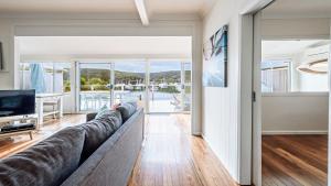ein Wohnzimmer mit Sofa und Fernseher in der Unterkunft 'Classic Cottage on the Bay' by HolidayCo in Hardys Bay