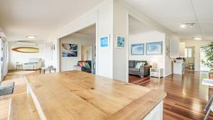 ein großes Wohnzimmer mit einem Holztisch. in der Unterkunft 'Classic Cottage on the Bay' by HolidayCo in Hardys Bay