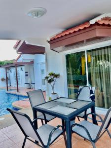 een tafel en stoelen op een patio met een zwembad bij Pattaya Pool Villa39A 300 mater to beach gate exit in Pattaya South