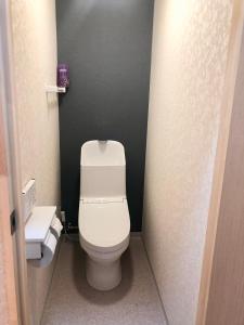 uma casa de banho com um WC branco e uma parede preta em Guest House Asahi em Otaru