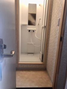 uma casa de banho com um chuveiro e um espelho. em Guest House Asahi em Otaru