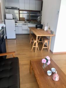 a living room with a table and a kitchen at Guest House Asahi in Otaru